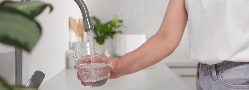Person getting water from a faucet with a water filtration system installation in Broward, FL improving clean, safe drinking water quality